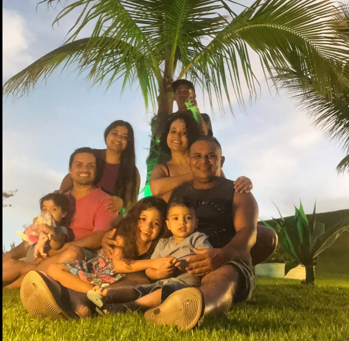 Família reunida embaixo do coqueiro ao pôr do sol